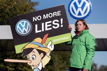 นักกิจกรรมจากกรีนพีซกับป้ายประท้วง Volkswagen ที่มาภาพ: http://www.businessinsider.com/this-is-the-real-cause-of-the-vw-cheating-scandal-2015-10